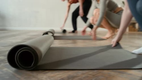 Unrecognizable Women Laying Out Yoga Mats Before Class in Fitness Studio