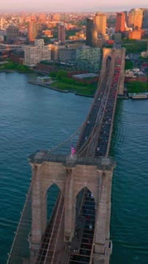 Wonderful Brooklyn Bridge with its heavy traffic. Beautiful yacht cutting the smooth surface