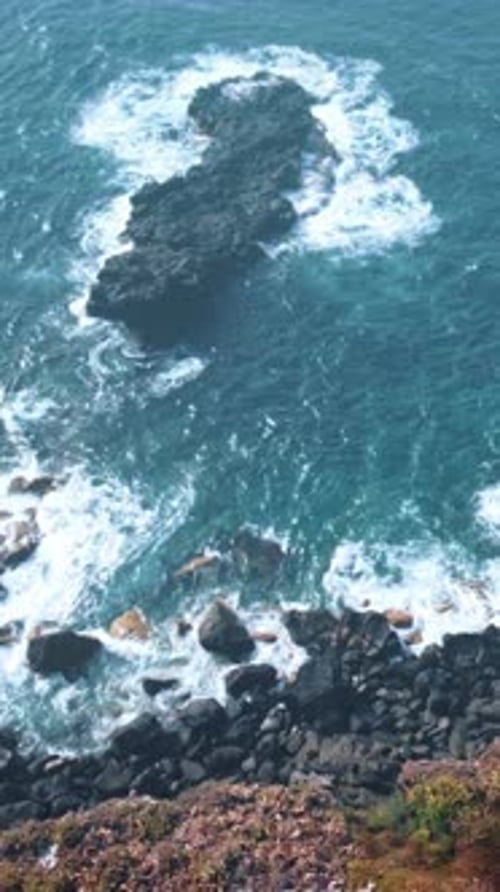 Ocean Waves Crashing on Rocky Shore Near Banana Plantation