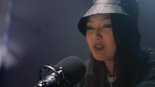 A Young Asian Girl Millennial DJ is Recording a Podcast in a Recording Studio Gives Interviews About
