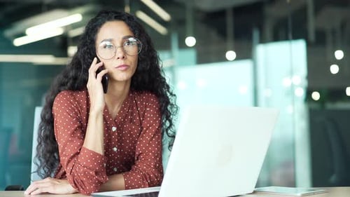 confident busy attractive business woman employee talking on the cell phone sitting in modern office
