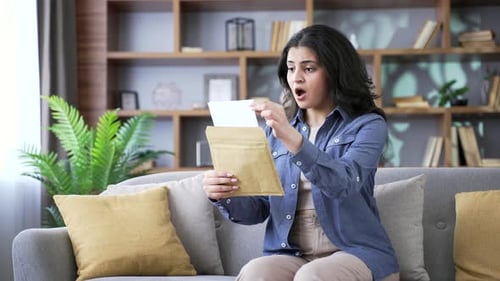 Woman receives good news in the mail, celebrates