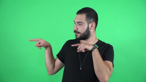 Mann zeigt mit beiden Handfingern auf grünem Bildschirm 4K in die linke Richtung