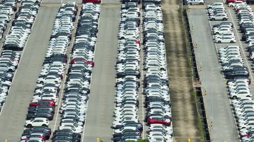 Rows of a new cars parked in a distribution center, by drone aerial view.