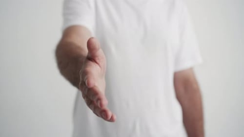 Homem estendendo o braço para apertar a mão em close-up. Um cara milenar esticando
a mão