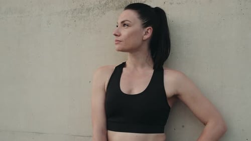 Woman in Athletic Wear Leaning Against a Wall