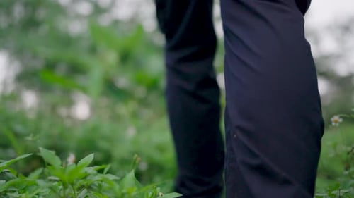 Niedriger Blick auf männliche Füße in Turnschuhen, die einen Pfad in der Nähe des Waldes entlang treten Die Beine des jungen Mannes gingen