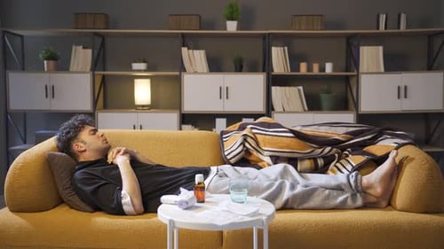 Woman Caring for Sick Young Adult Man on Couch