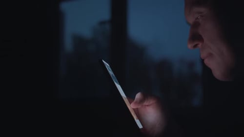 Man Uses Tablet in Dark Room at Night