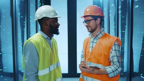 Two Construction Workers Discuss Their Ongoing Project in a Hightech Modern Environment