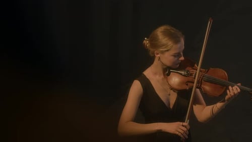 Woman Playing Violin in Dark Room