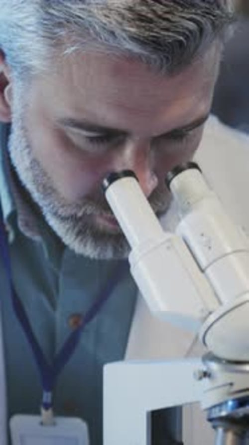 Man Works with Microscope in Medical Research Lab