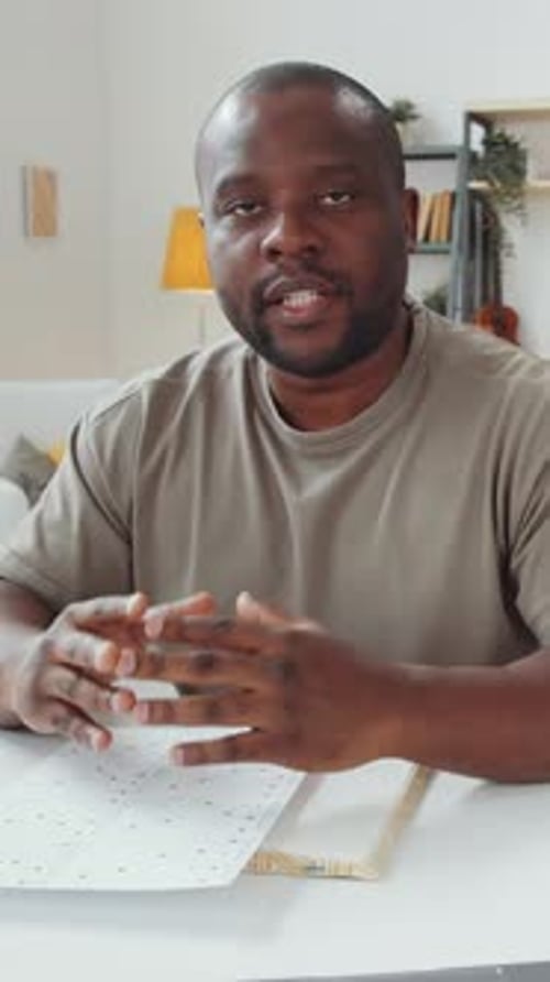 Black Man Looking at Camera and Explaining Graphs on Paper