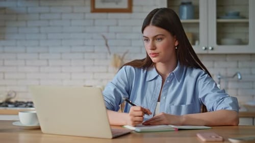 Woman Working on Laptop and Writing in Notebook