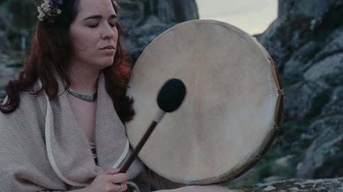 spiritual woman peacefully playing a shamanic drum in a beautiful medieval village medium close deta
