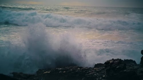 Foaming ocean waves crashing on rocky coastline stones in dramatic slow motion