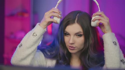 Young Woman Placing Headphone Under Pink Purple Ambient Live Stream Setup