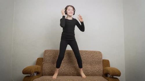 Girl Dancing with Headphones on Couch at Home