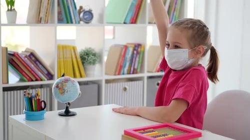 Young Child Raising Hand in School with Medical Mask