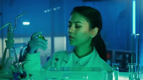 Une médecin asiatique examine un flacon de liquide vert dangereux ou de poison