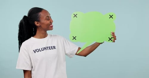 Happy black woman, volunteer and pointing to speech bubble for social media against a studio