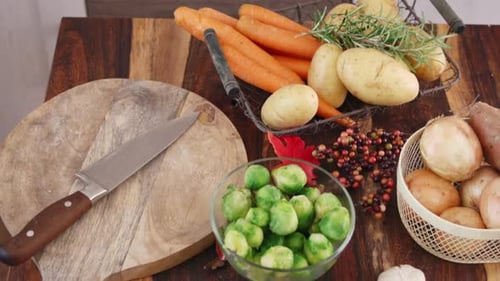 Hands Placing Raw Whole Turkey on Table with Fresh Autumn Vegetables