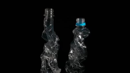 Crushed Plastic Bottles on Black Reflective Surface