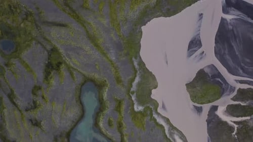 Aerial top down shot of glacial river in volcanic landscape of Iceland at cloudy day - flyover