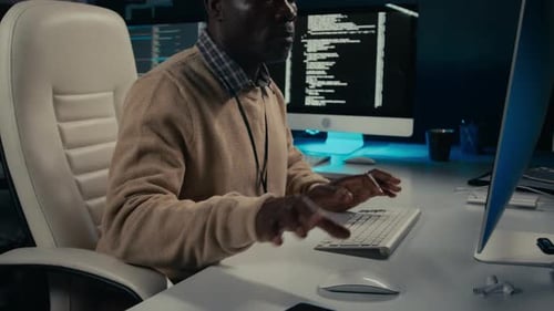 Adult Working at Computer Takes Phone Call