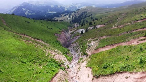 Mountain landscape of canyon between slanted green hills, descending drone flight