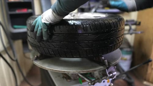 Ein Arbeiter entfernt in einer Werkstatt Reifen von einer Felge