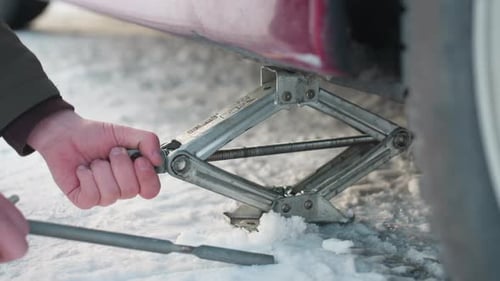 Man Jacking Up Car in Winter
