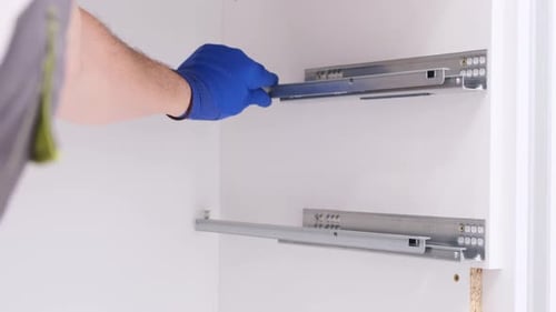 A Man Installs Furniture in the Kitchen with a Screwdriver