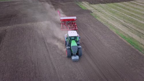 Agricultural tractor sowing crops on a cultivated field drone view