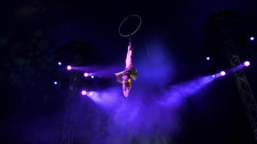 Woman Performs Aerial Acrobatics on Hoop Under Blue Lights