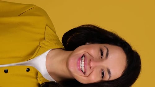 Happy Young Lady Posing in Studio While Throwing Up an Orange and Showing It at Camera Isolated on