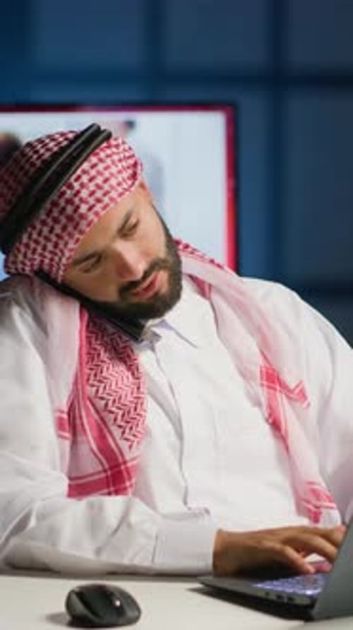 Man in Headscarf Works and Talks on Phone