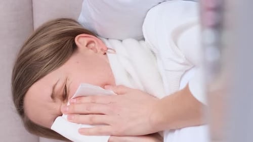 Vidéo verticale d'une femme enrhumée d'apparence européenne allongée sur un lit avec une gorge bandée