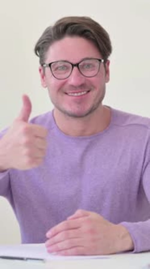 Smiling Man Gives Thumbs Up at Desk Indoors