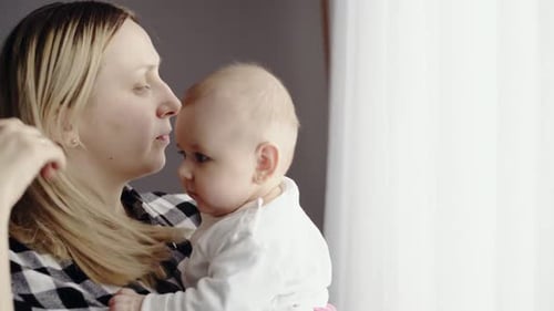 Loving Mother Cuddles Adorable Baby Indoors