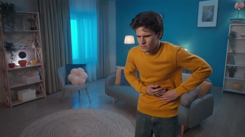 Young Man with Stomach Pain in Cozy Interior
