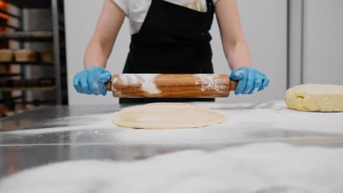 The kitchen in the bakery - the process of preparing cinnabons, the woman baker forms doughs