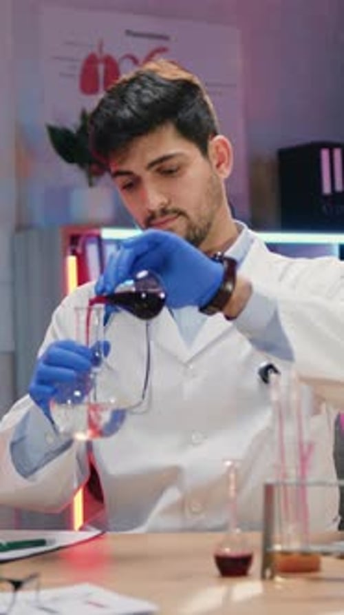 Focused Young Adult Medical Professional Mixing Liquids in Lab