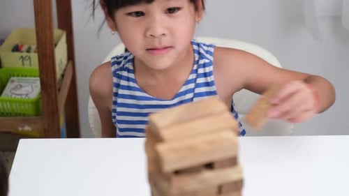 Cute Asian siblings having fun playing Jenga together.