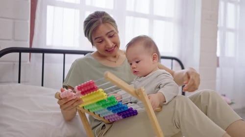 Loving Mother and Baby Play with Toy on Bed