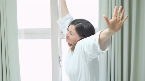 Woman stretching in morning and open curtains side view, early wake up concept.