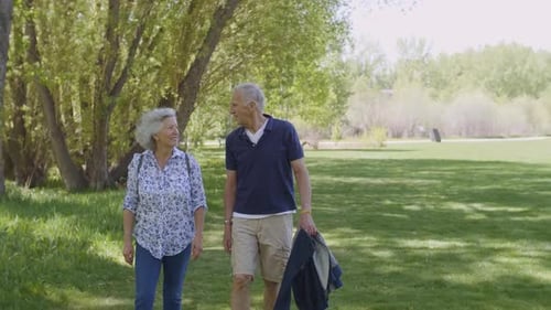 Slow Motion Of Cheerful Senior Couple Enjoying Relaxing Walk In Park