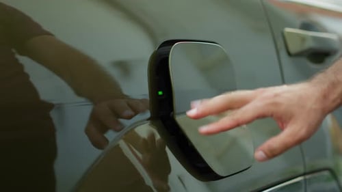 Nahaufnahme eines umweltbewussten Fahrers, der die Ladeanschlussklappe eines Elektroautos öffnet