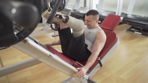 Disabled Athletic With leg prothesis does heavy workout for his legs at the gym