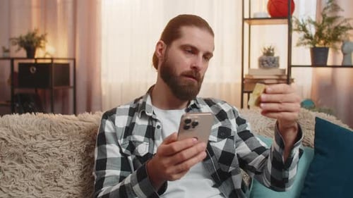 Man shops online with phone and credit card